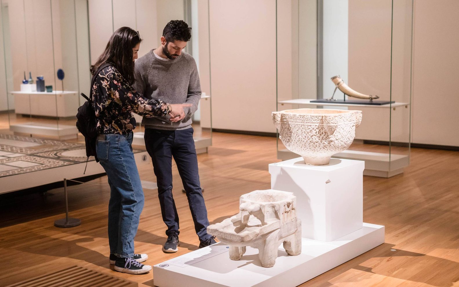 Young couple examining and discussing a stone artifact in the Aga Khan Museum permanent Collections gallery