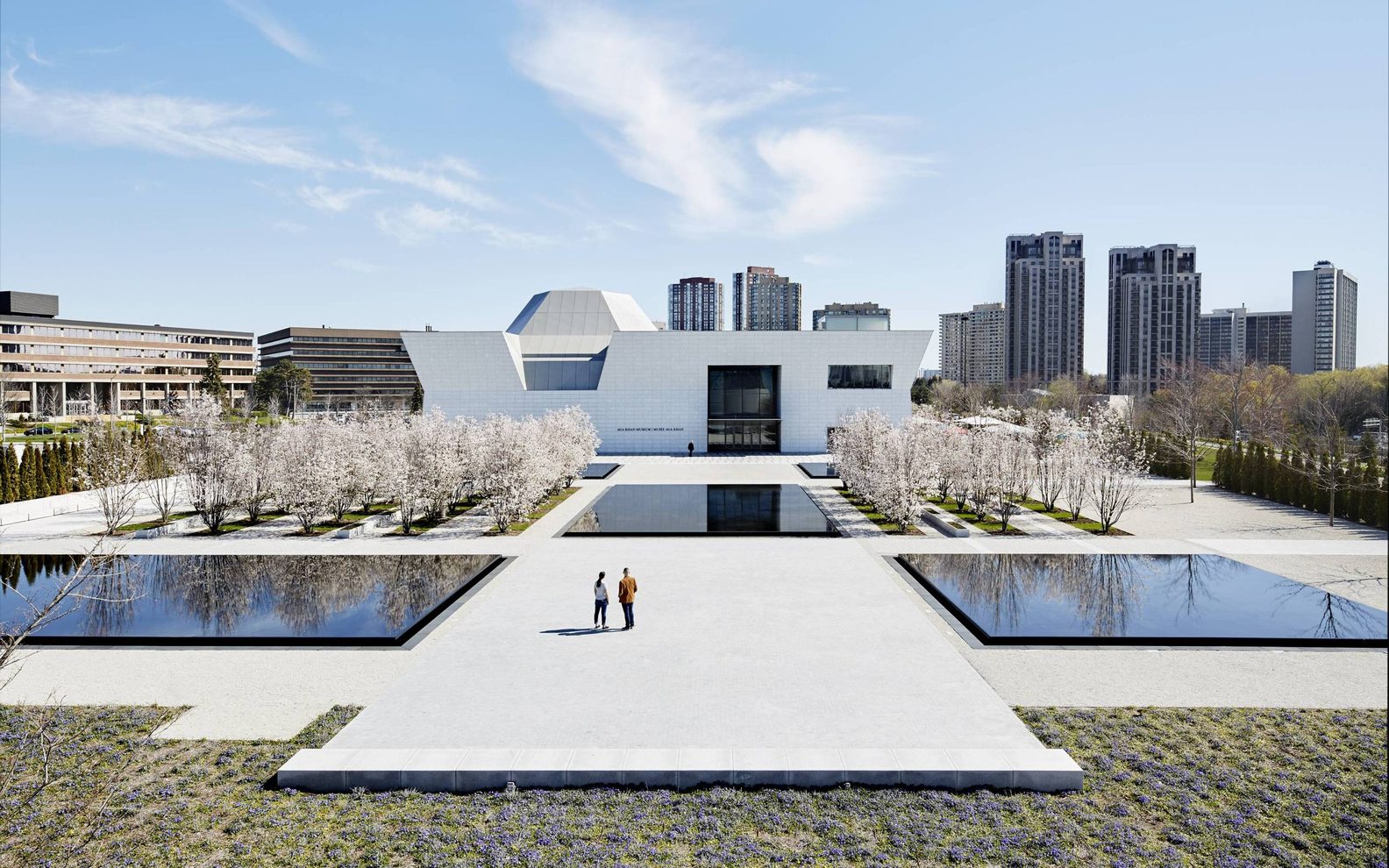Two people viewing the front entrance of the Aga Khan Museum from the courtyard