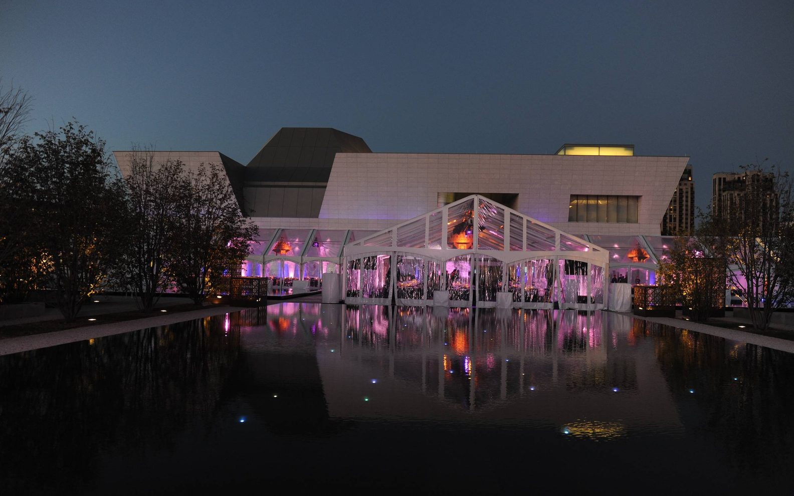 Wide exterior view of the Aga Khan Museum main entrance with a special events tent at night