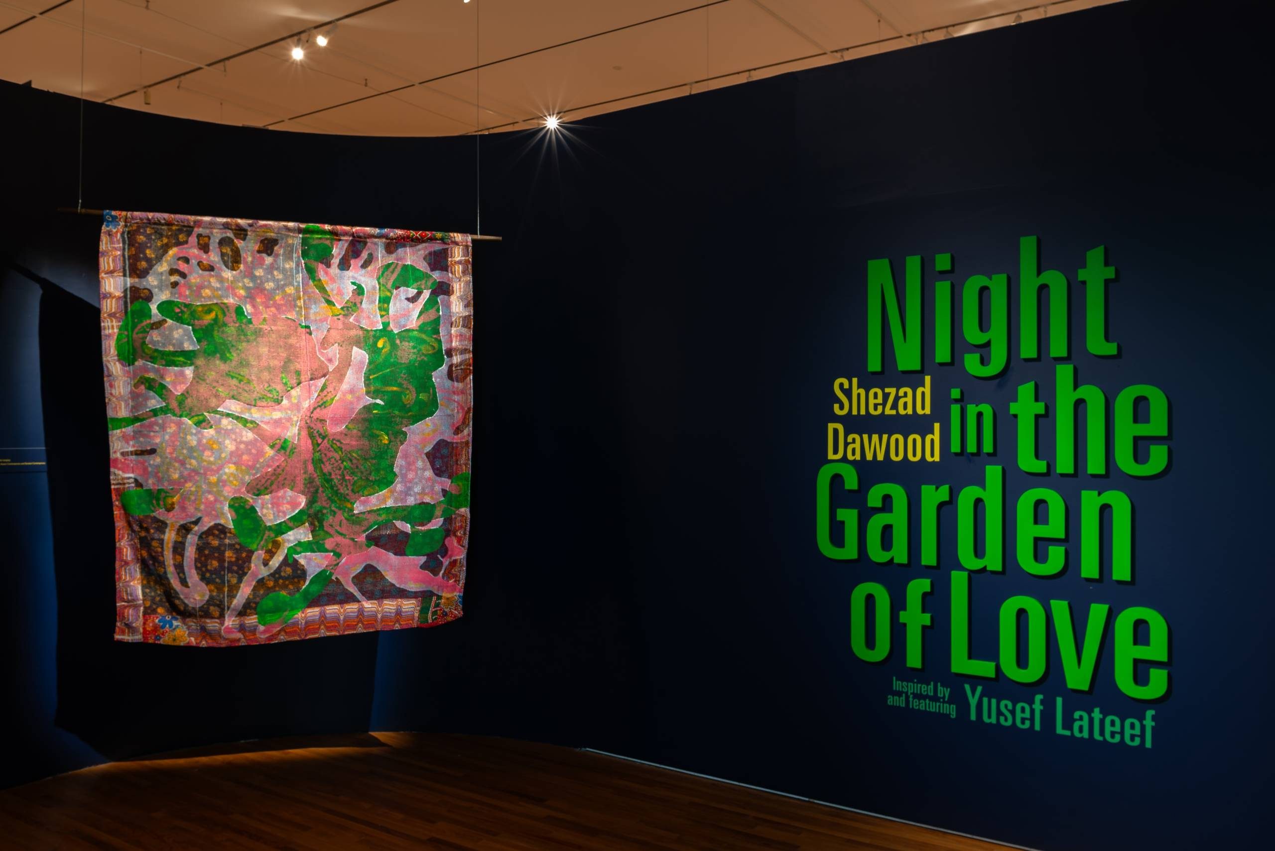 Entrance to the Night in the Garden of Love exhibition displaying a textile to the left and the title to the right