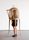 A young woman stands underneath a chair with a wicker cage over it, used to contain the birds.